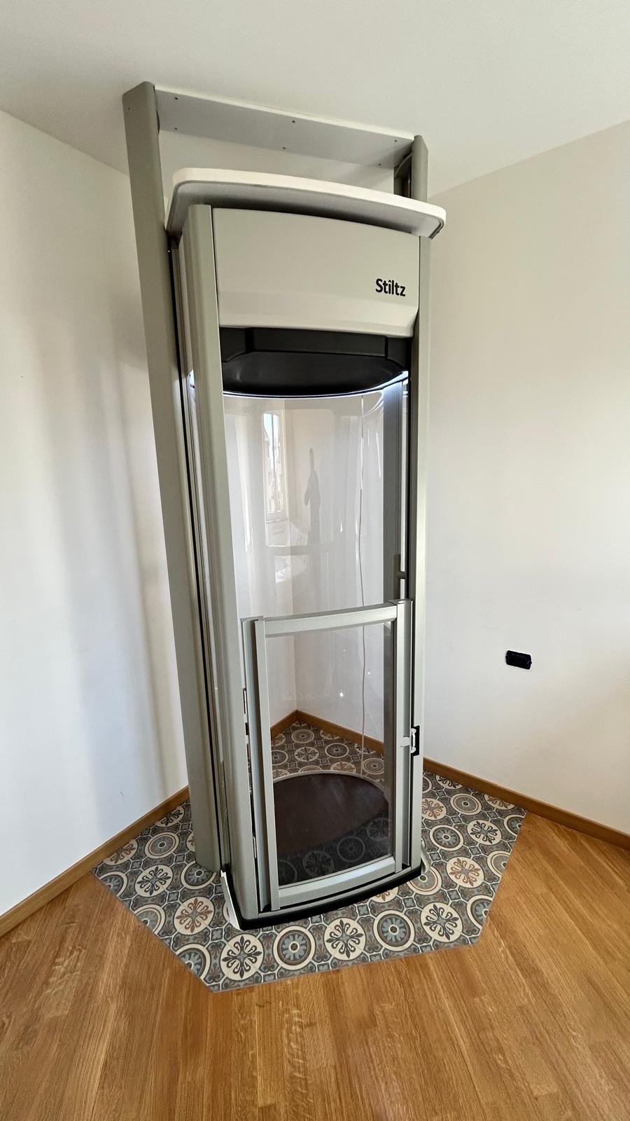 Elegant mini ascensore installato in appartamento con parquet e mattonelle colorate